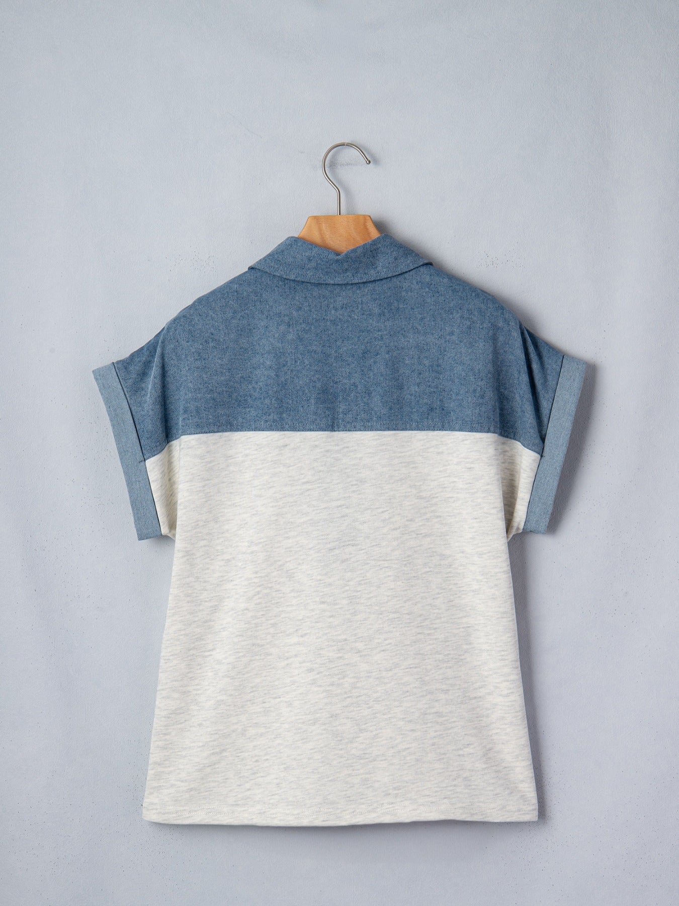 Two-tone blue and gray shirt on a hanger against a light gray background