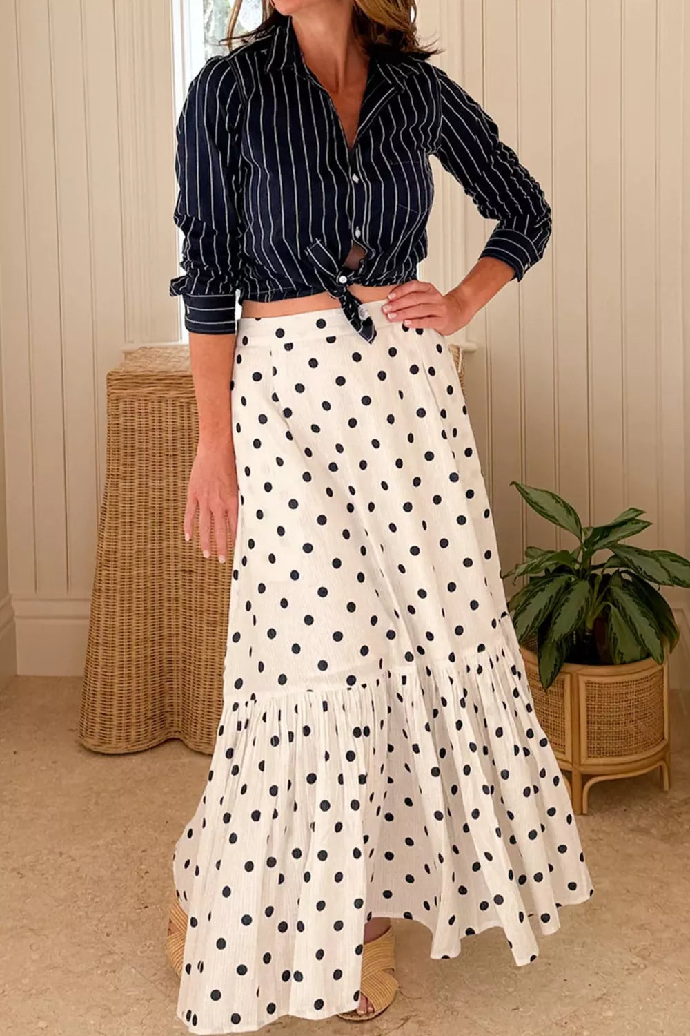 Woman wearing a striped shirt and polka dot skirt in an indoor setting.