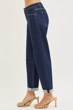 Dark blue jeans worn by a person on a white background