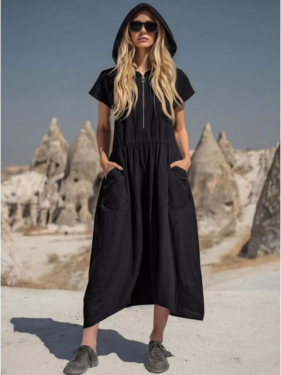 Woman wearing a black hooded dress with stone formations in the background