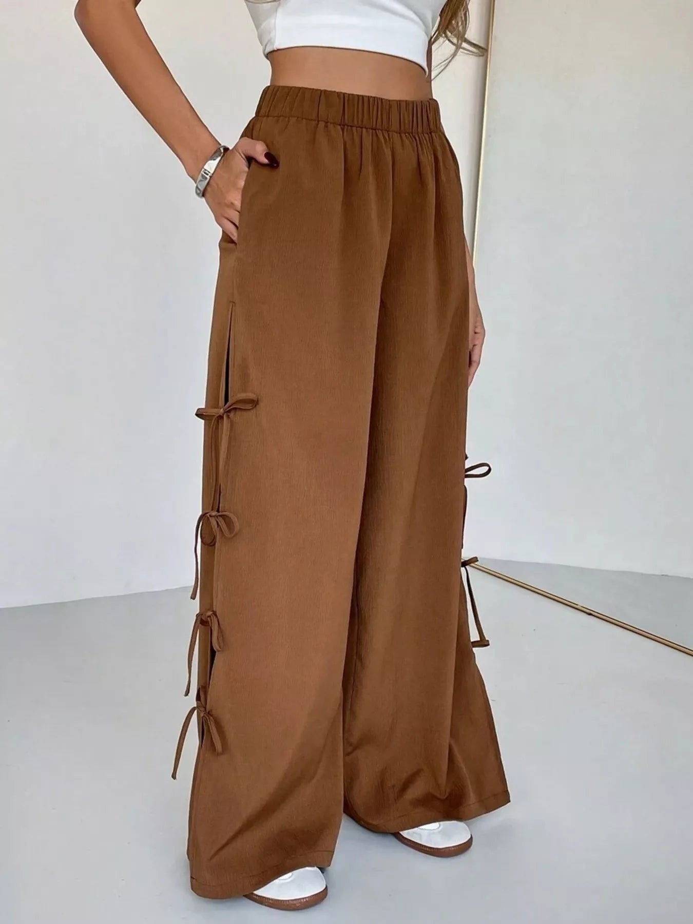 Brown wide-leg pants with tie details on a white background