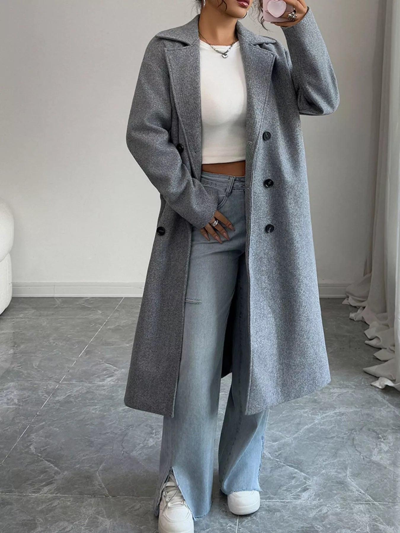 Person wearing a long gray coat in an indoor setting