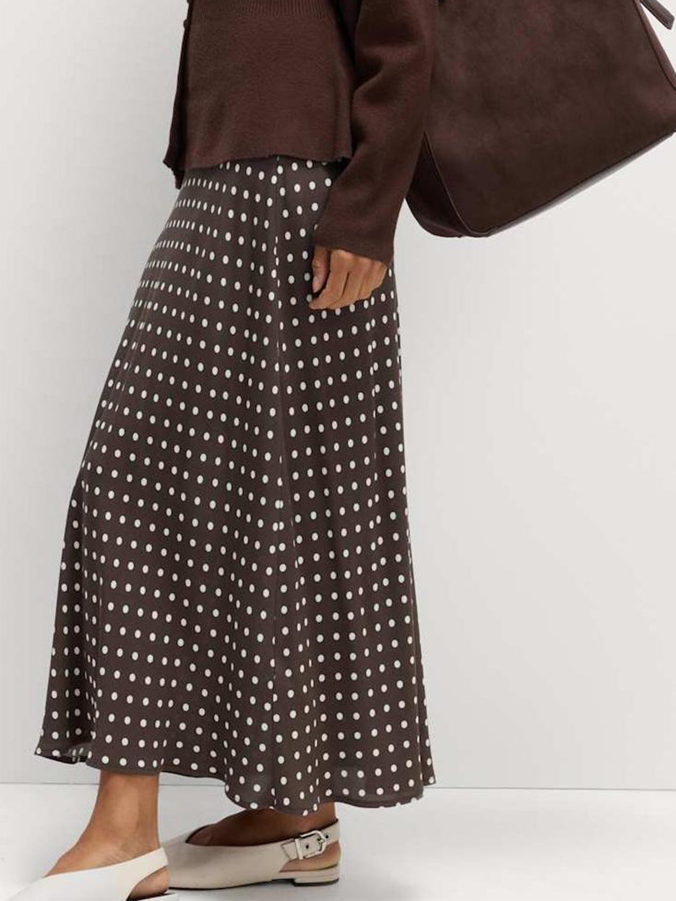 Person wearing a brown polka dot skirt with a plain background