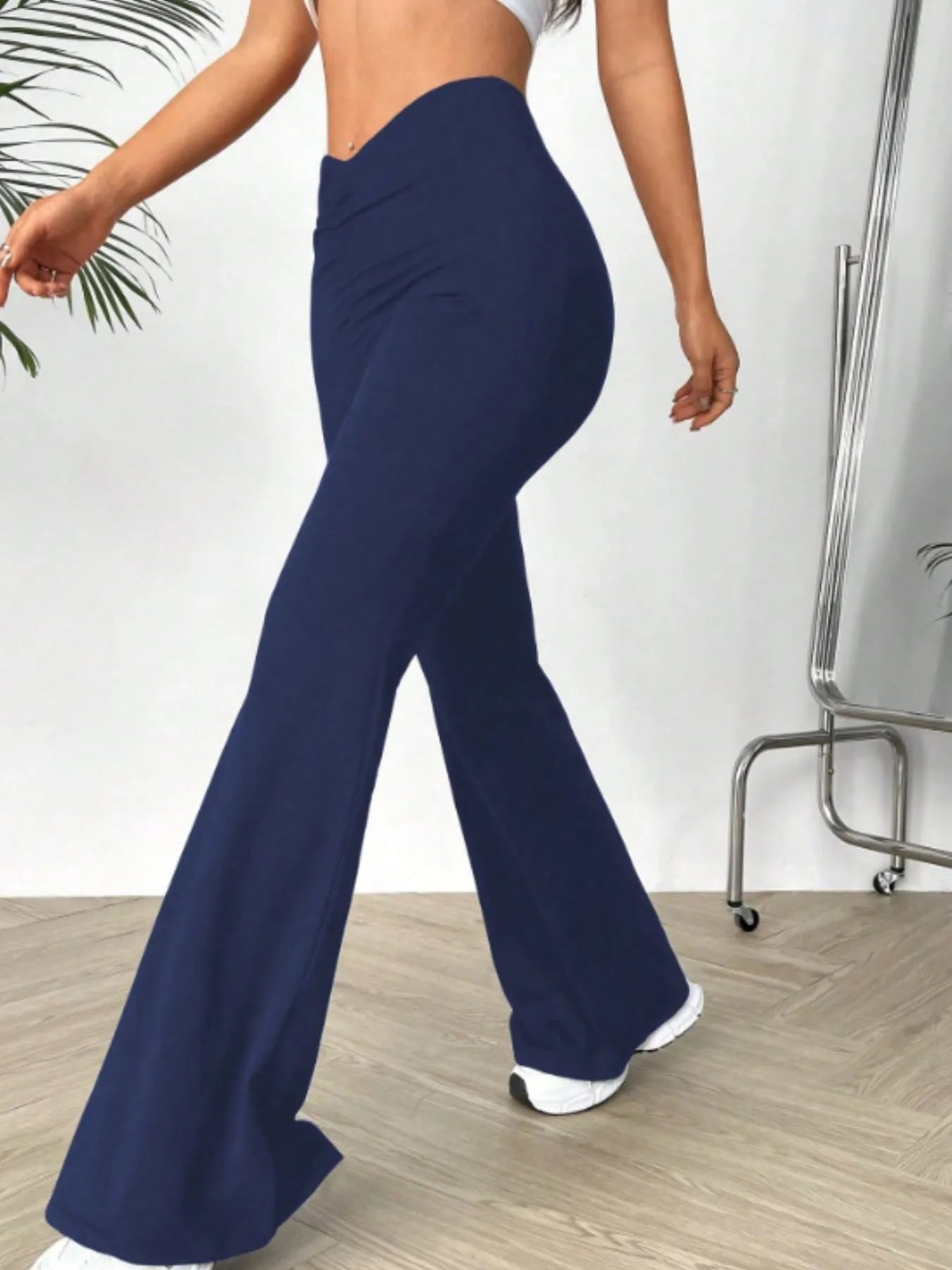 Person wearing navy blue flared pants on a light wooden floor.