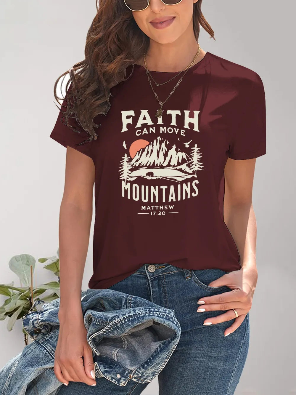 Person wearing a maroon t-shirt with 'Faith can move mountains' graphic design.