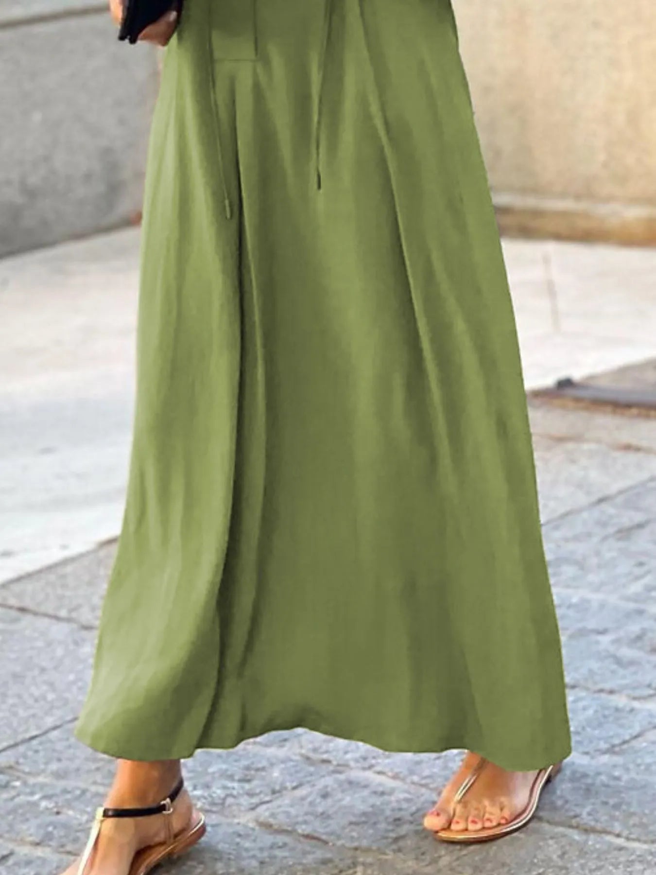 Green dress worn by a person on a stone pavement