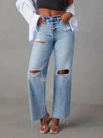 Person wearing ripped blue jeans on a gray background