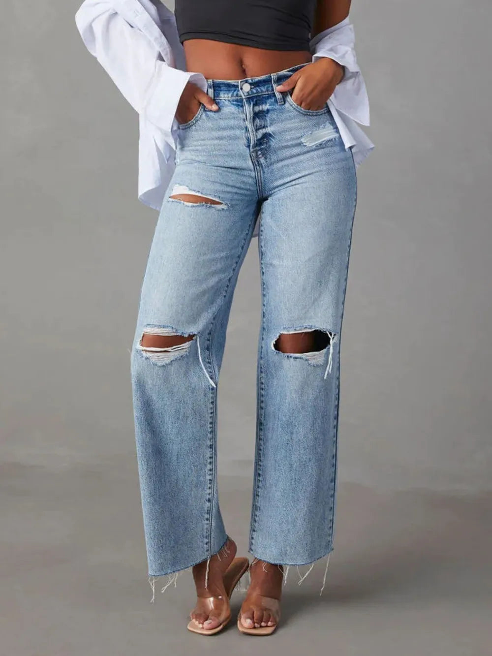 Person wearing ripped blue jeans on a gray background
