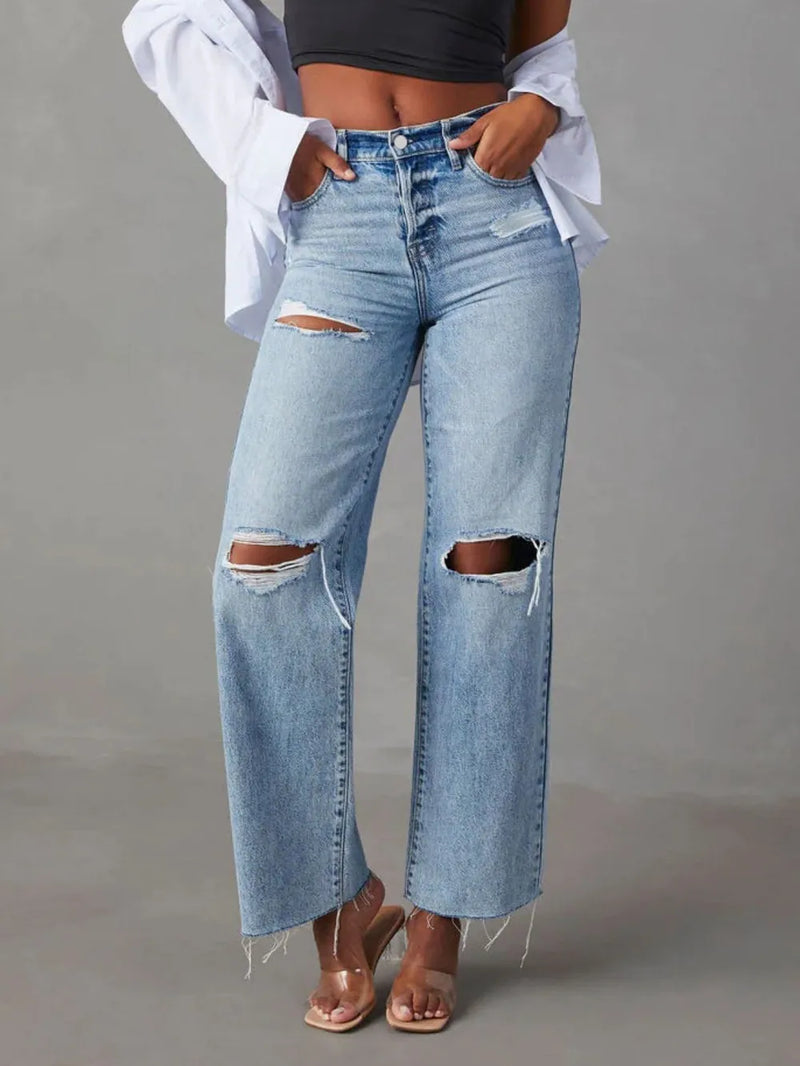 Person wearing ripped blue jeans on a gray background