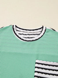 Green sweater with black and white striped details on a beige background