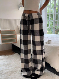 Person wearing black and white checkered pants in a bedroom setting