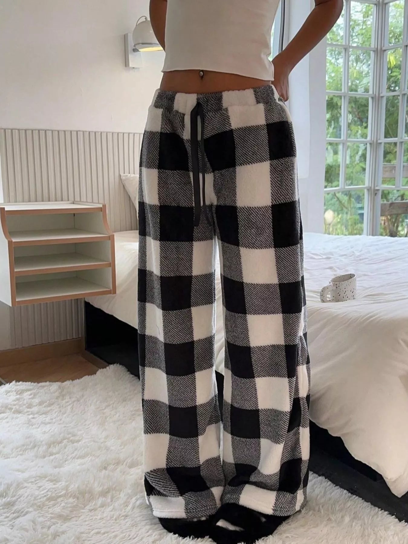 Person wearing black and white checkered pants in a bedroom setting
