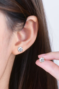 Close-up of an ear with diamond stud earrings and a hand holding another pair.