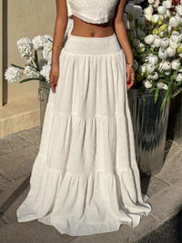 Person wearing a white dress standing in front of flowers