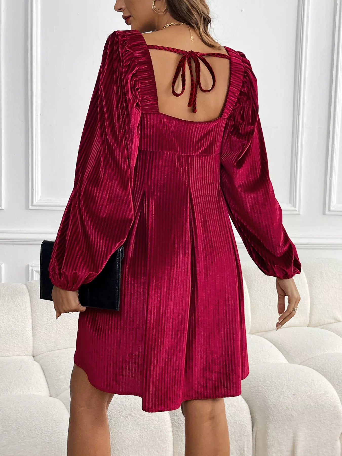 Woman wearing a burgundy velvet dress with long sleeves in an indoor setting.