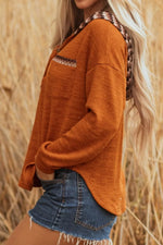 Person wearing an orange long-sleeve shirt and denim shorts standing in a field of tall grass.