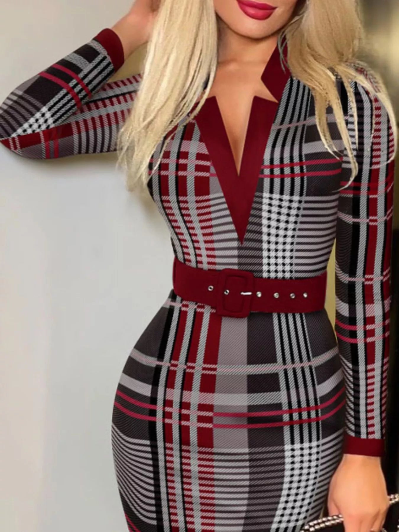Woman wearing a plaid dress with red accents against a white background