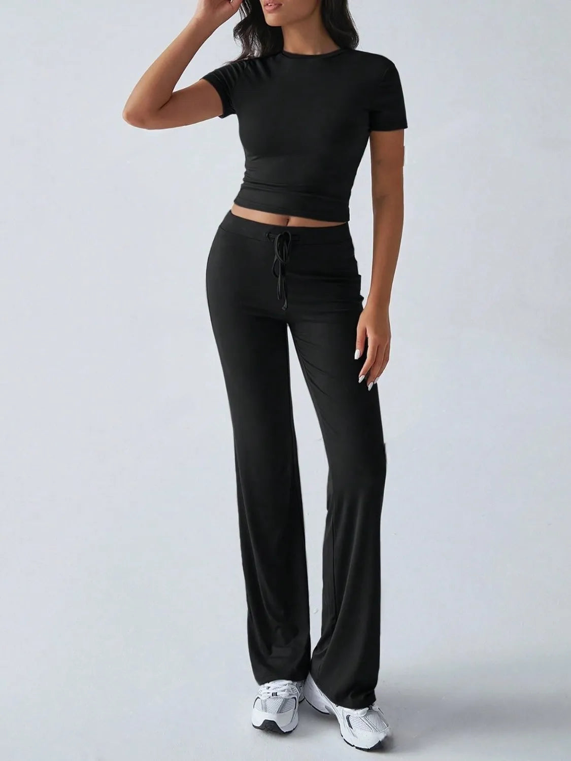 Person wearing a black outfit with wide-leg pants on a white background