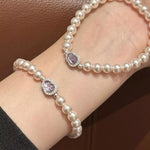 Pearl bracelet with purple gemstones on a wrist against a brown background