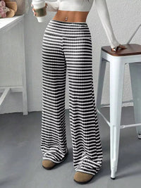 Person wearing black and white striped pants in a minimal indoor setting