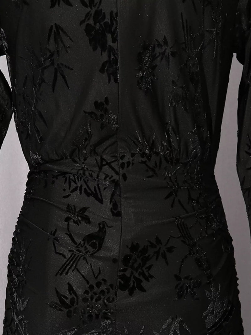 Close-up of a black long-sleeve dress with tonal floral and bird embroidery, showing the back waist and center seam.
