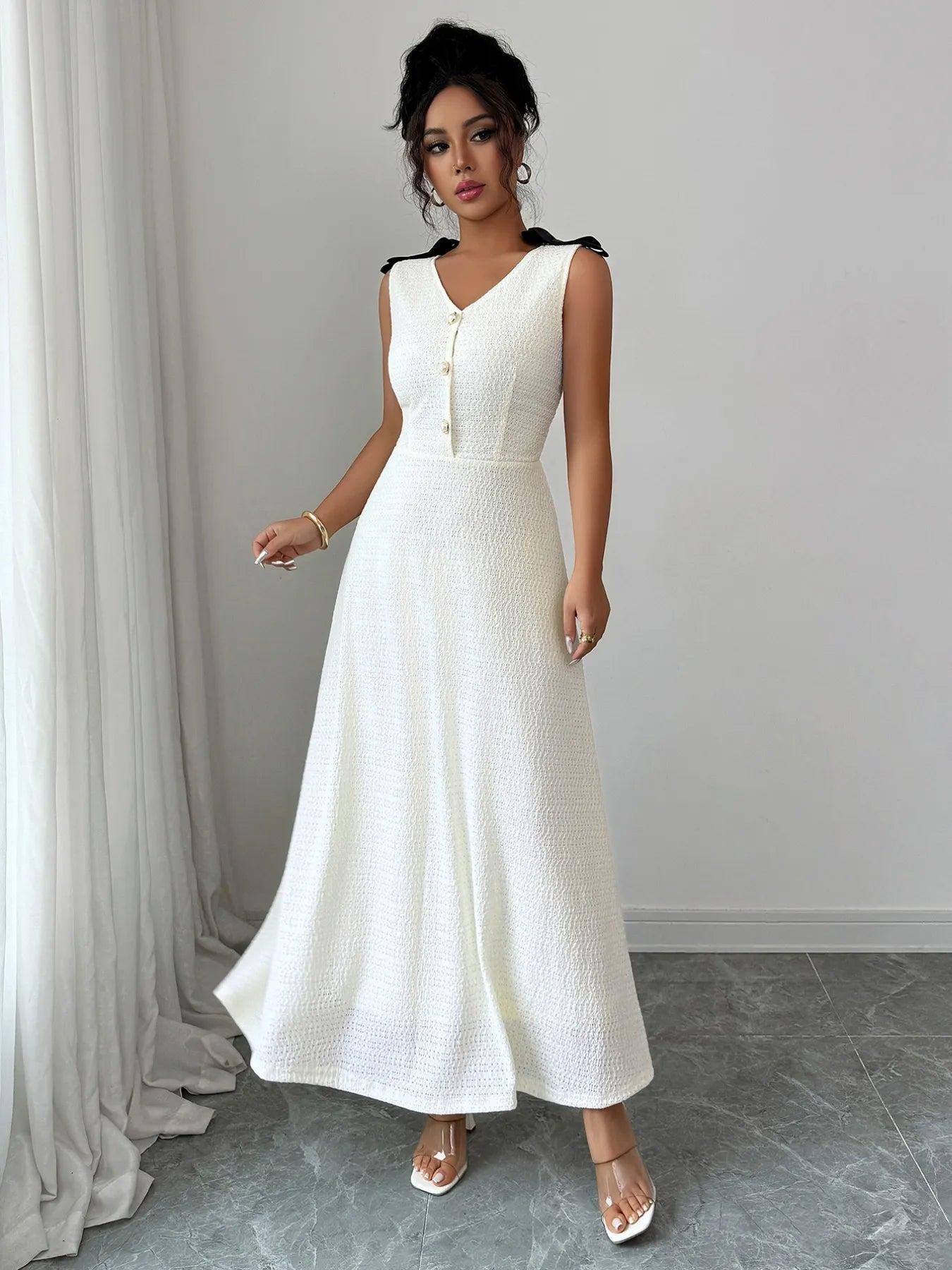 Woman wearing a white dress with black accents against a plain background