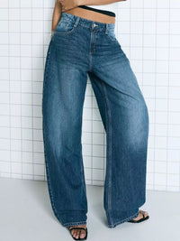 Person wearing wide-leg jeans against a white tiled wall.