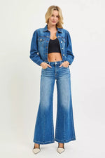 Woman wearing a blue denim jacket and jeans on a white background
