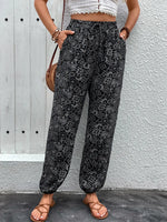 Person wearing black patterned pants against a gray wall