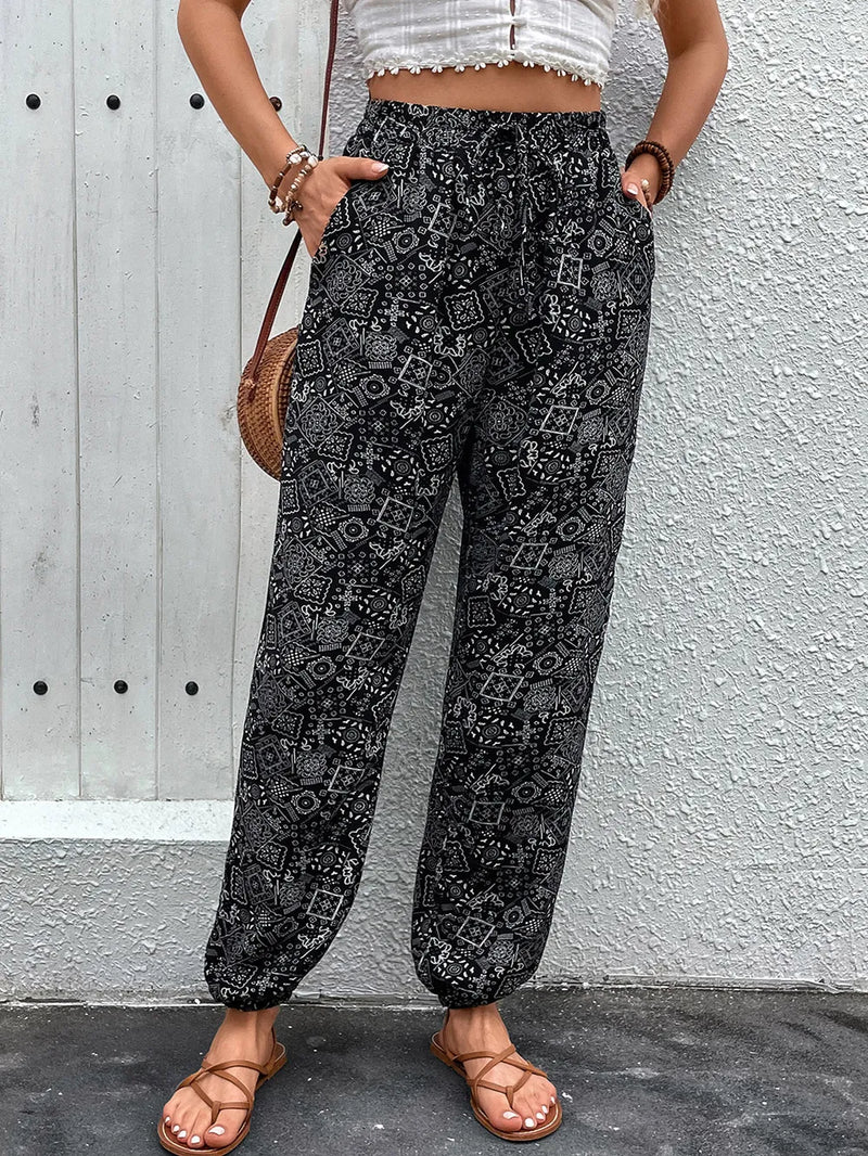 Person wearing black patterned pants against a gray wall