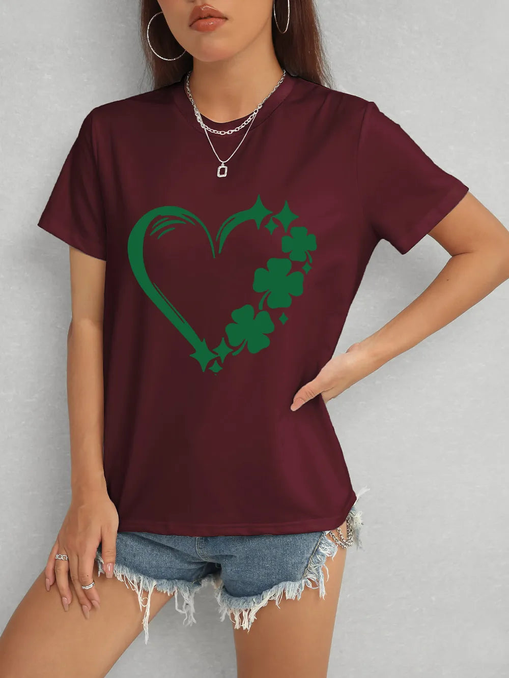 Person wearing a maroon t-shirt with a green shamrock design on a gray background