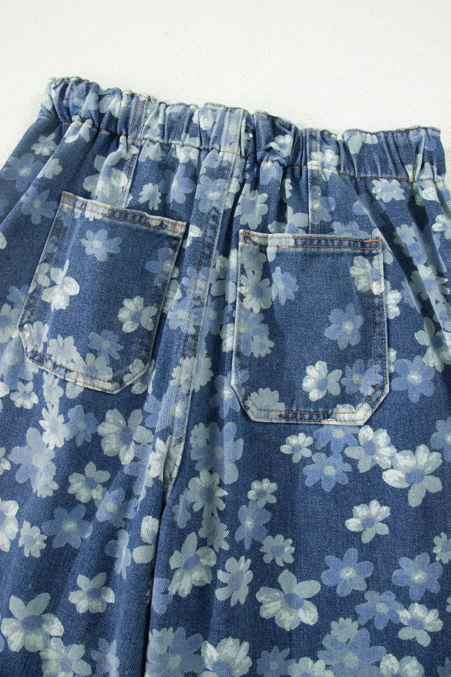 Blue denim skirt with white floral pattern on a white background