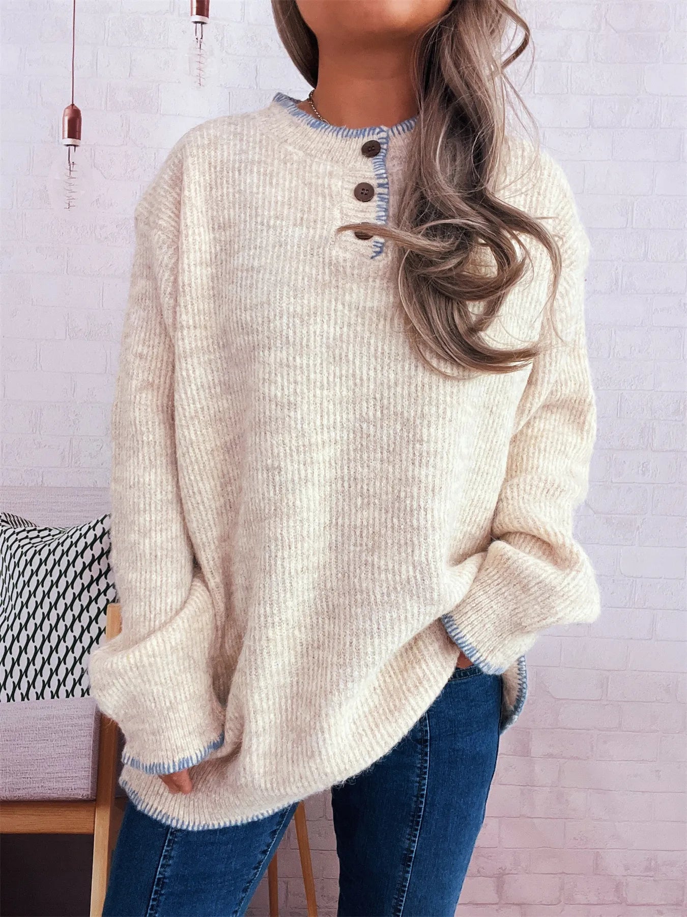 Person wearing a beige sweater with button details against a light background
