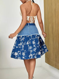 Woman wearing a blue floral skirt with a white top against a neutral background