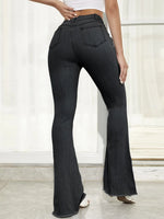 Person wearing black flared jeans on a white background