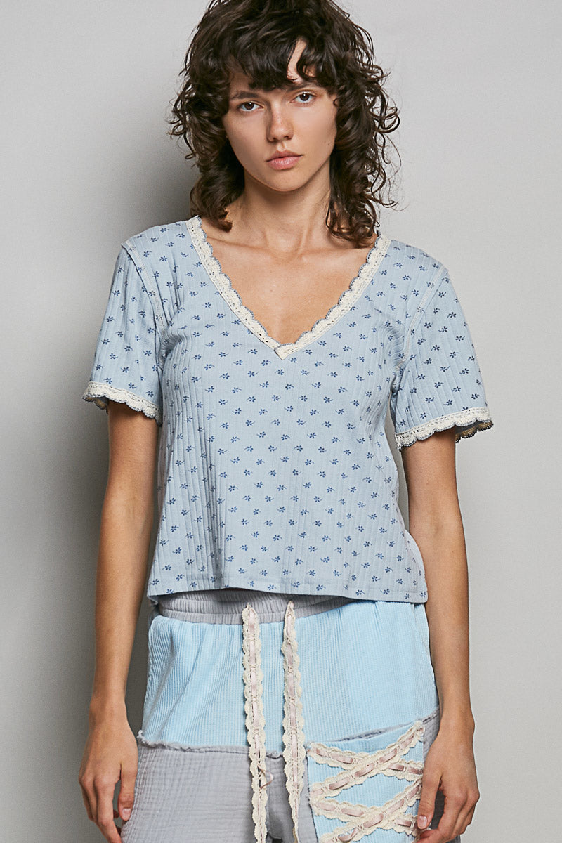Woman wearing a light blue patterned top and pants against a plain background