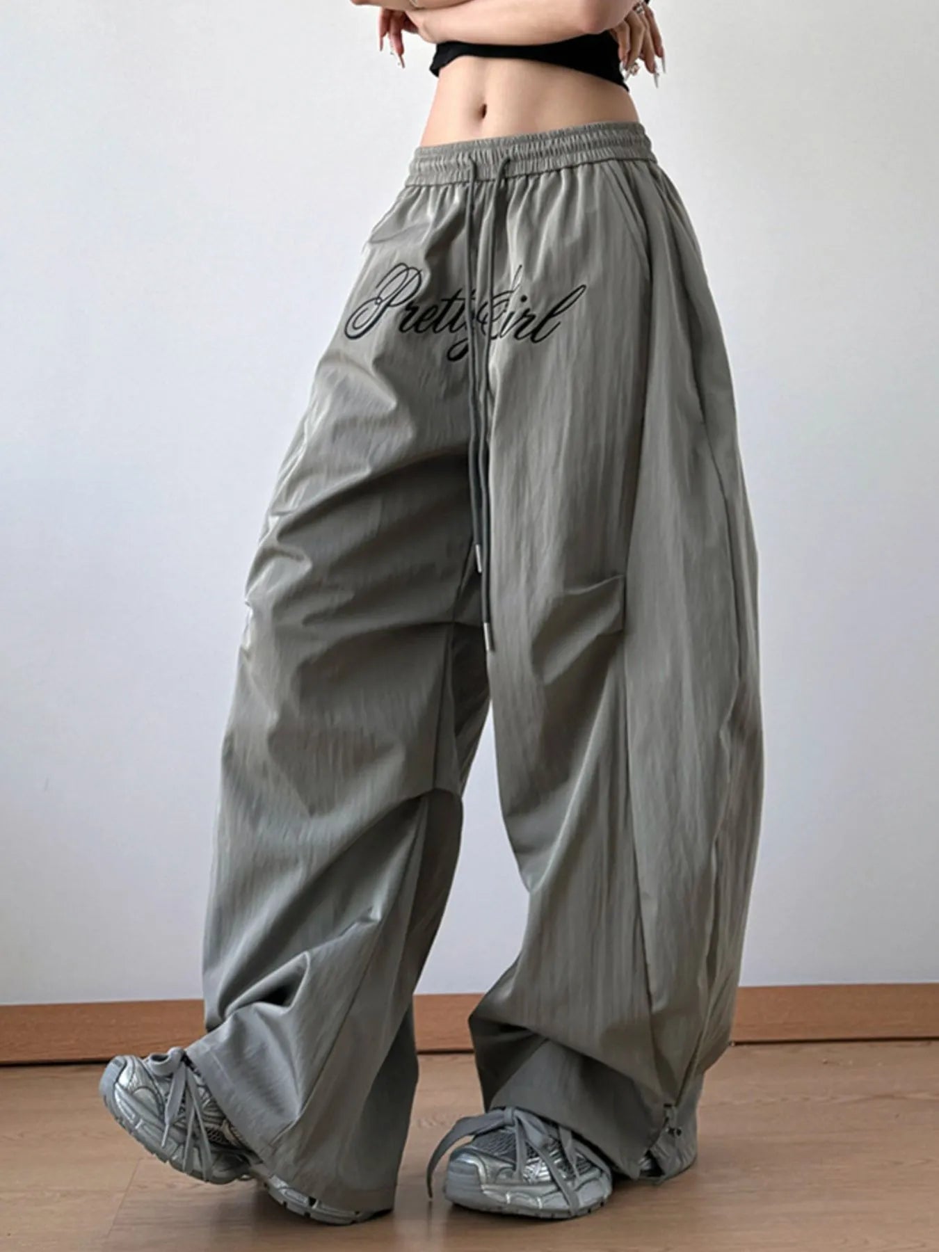 Person wearing gray wide-leg pants with 'PrettyGirl' text on a plain background