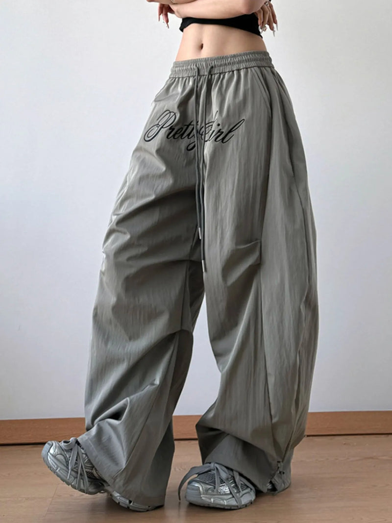 Person wearing gray wide-leg pants with 'PrettyGirl' text on a plain background