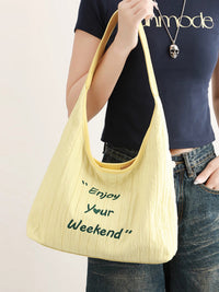 Person holding a yellow tote bag with 'Enjoy Your Weekend' text.