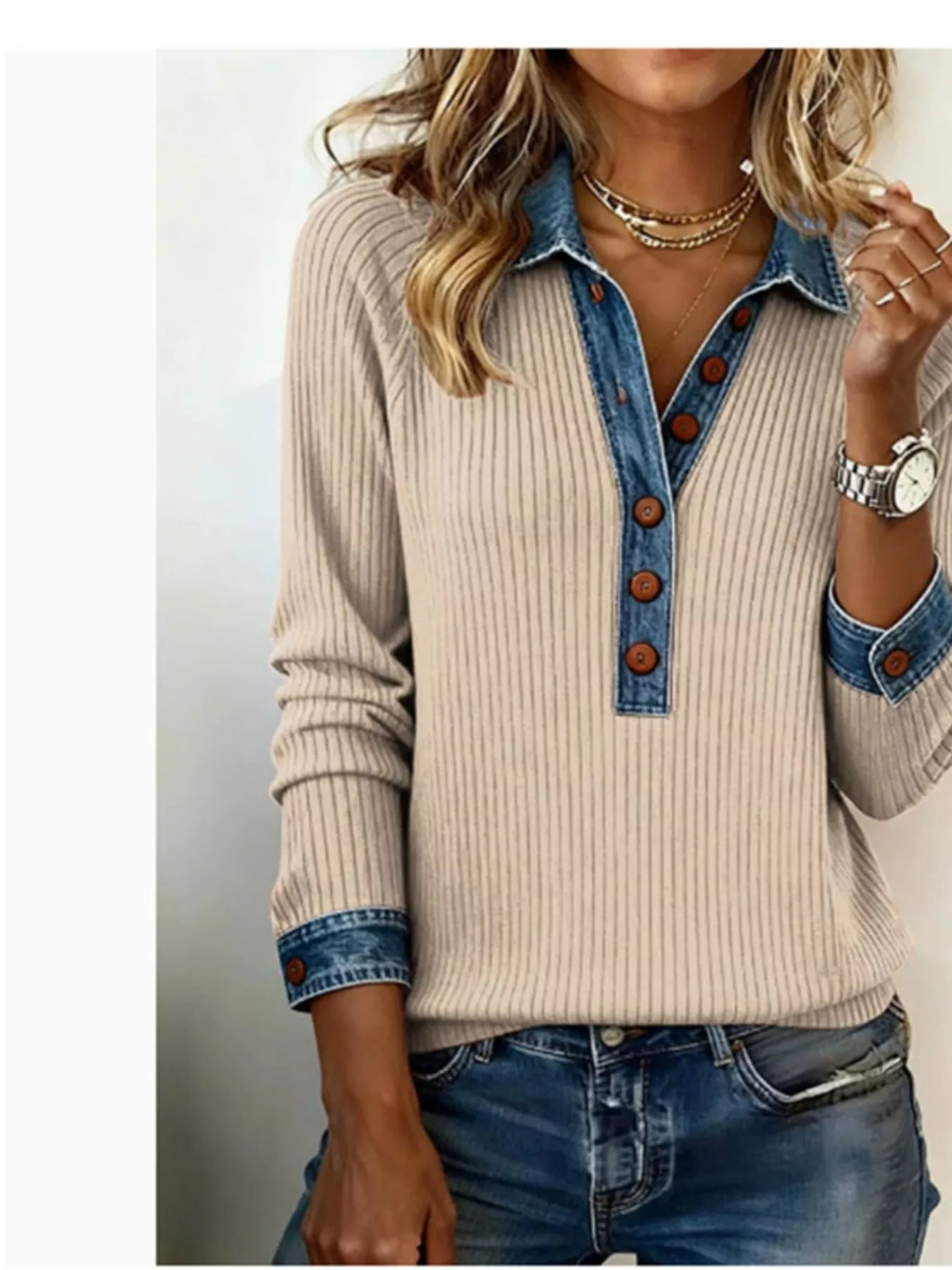 Beige sweater with denim collar and cuffs worn by a person on a plain background