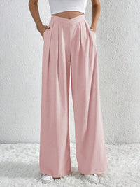 Person wearing light pink wide-leg pants on a white background