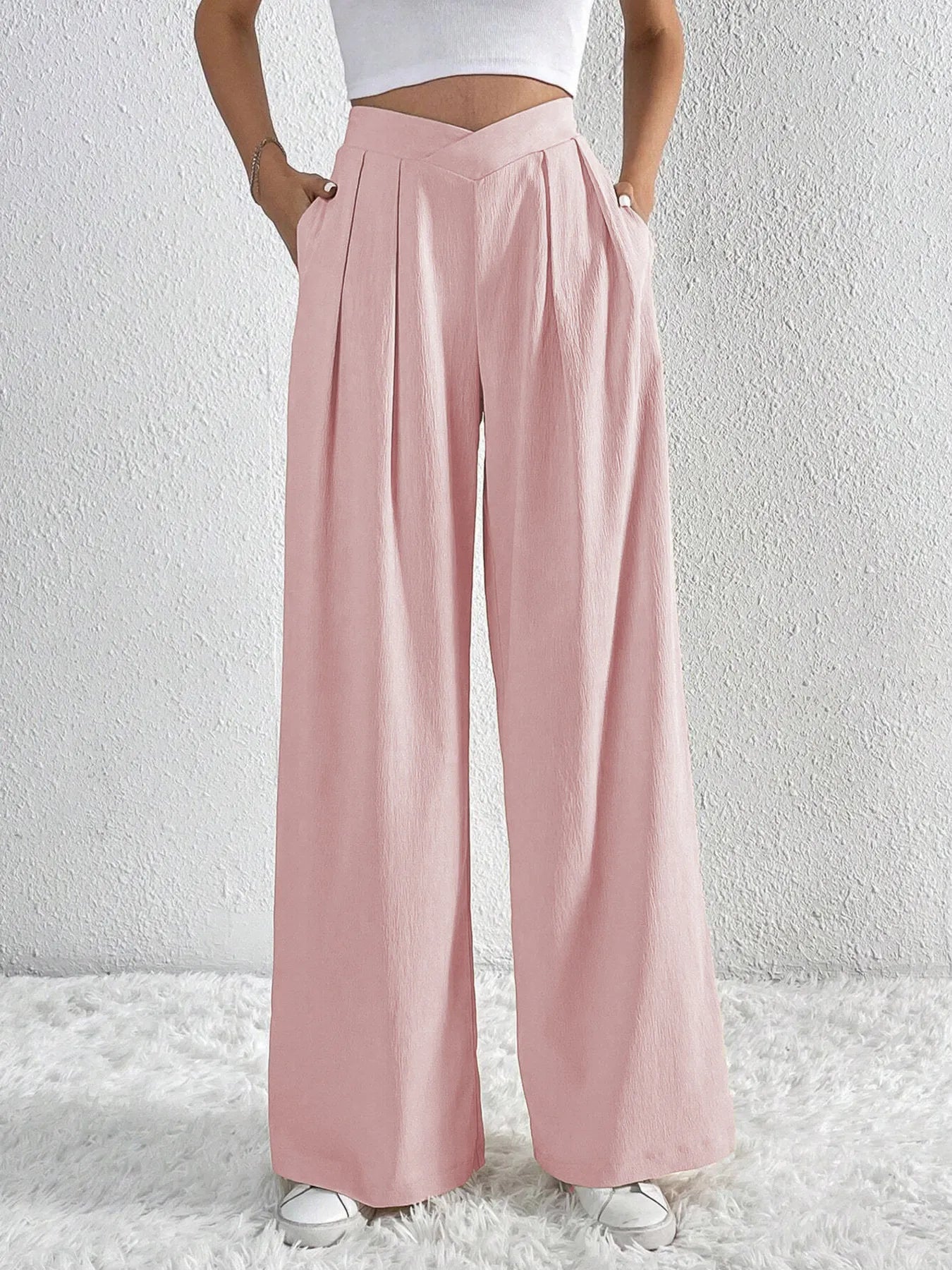 Person wearing light pink wide-leg pants on a white background