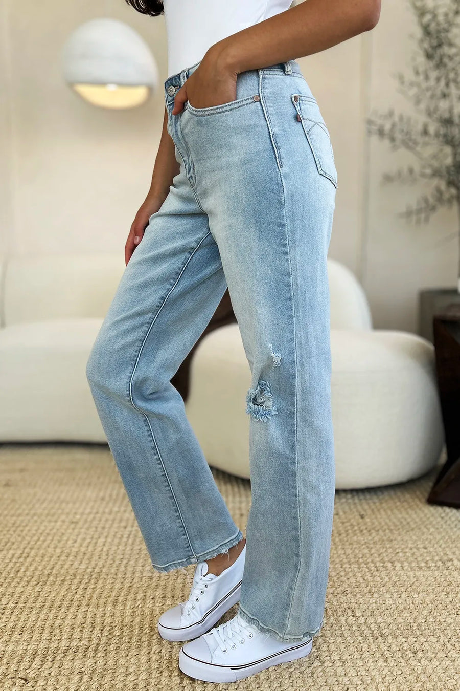 Person wearing light blue jeans and white sneakers in a casual setting