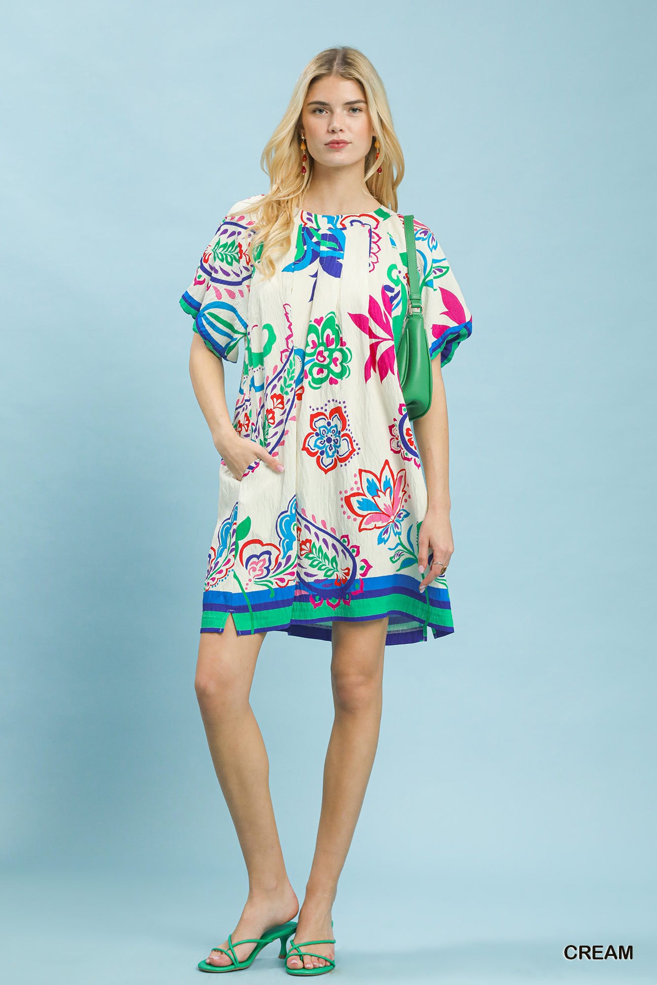 Woman wearing a colorful patterned dress on a light blue background