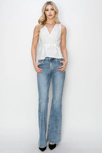Woman wearing a white sleeveless top and blue jeans on a white background