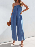 Woman wearing a blue denim jumpsuit against a white background