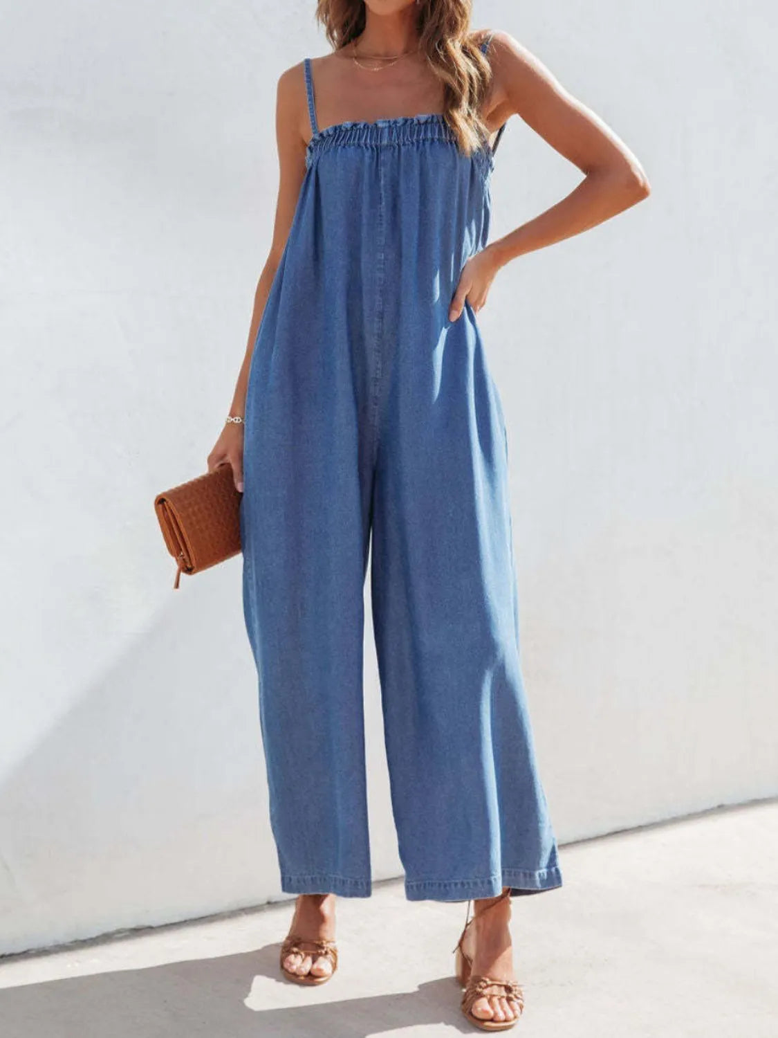 Woman wearing a blue denim jumpsuit against a white background