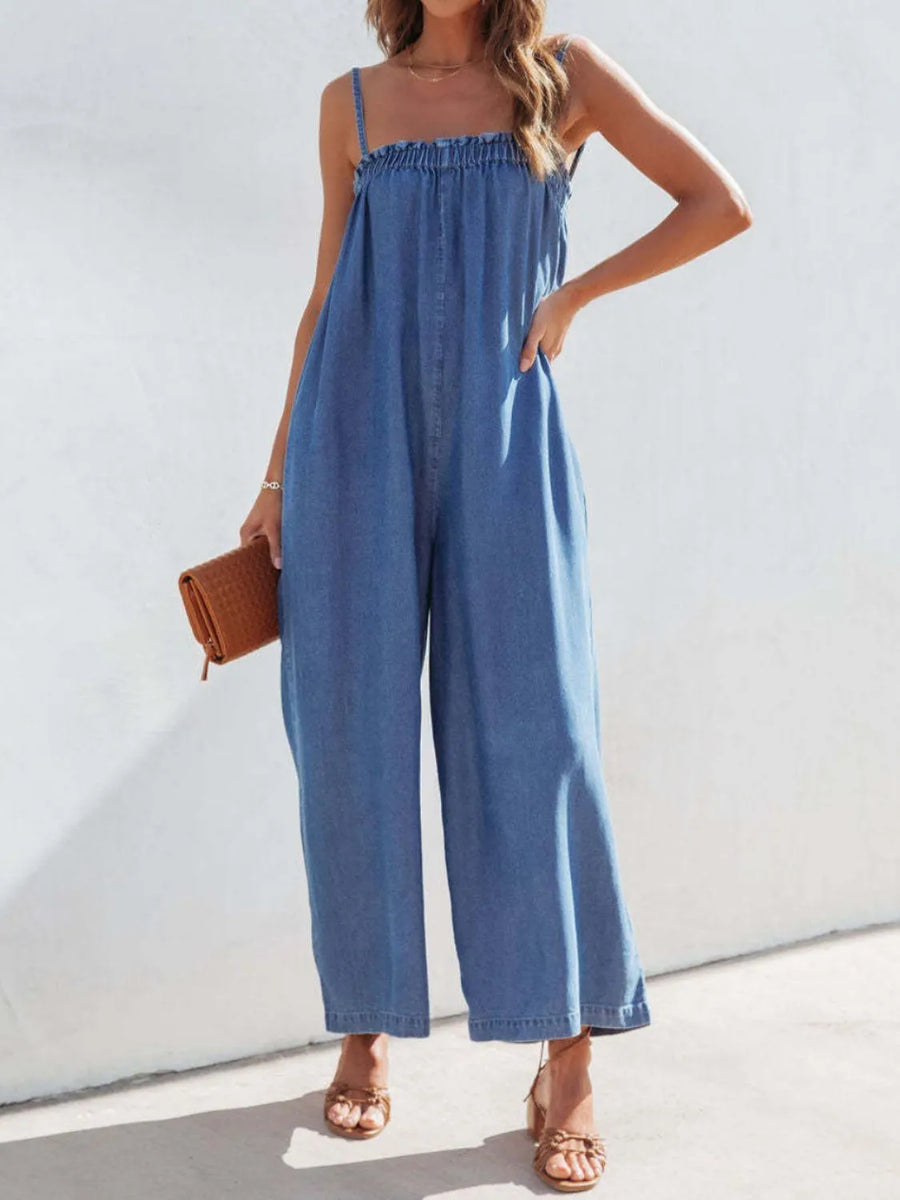 Woman wearing a blue denim jumpsuit against a white background