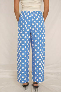 Blue pants with white polka dots worn by a person on a plain background