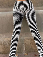 Black and white horizontally striped fuzzy knit flare leggings worn by a model standing against a concrete wall.